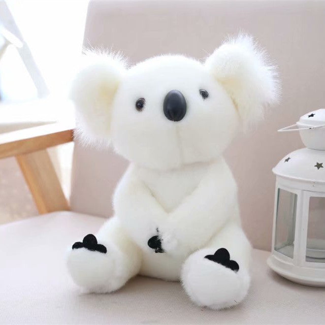 Soft white koala plush toy for kids sitting on a couch beside a decorative lantern