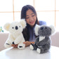 Woman holding white and grey koala plush toy for kids sitting at table indoors
