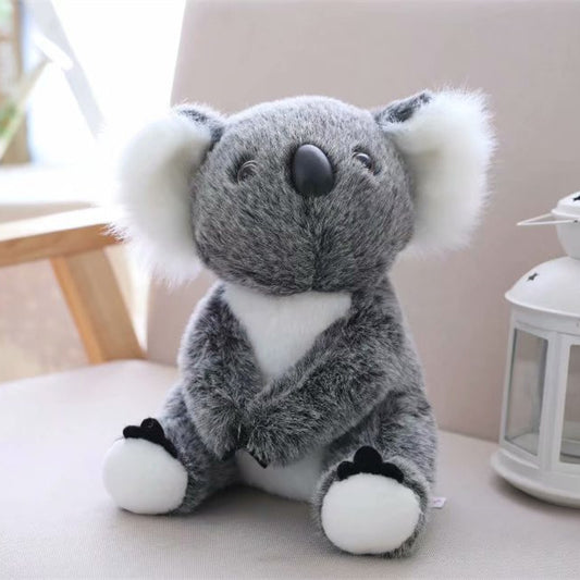 Soft gray and white koala plush toy for kids sitting on a beige chair near a white lantern